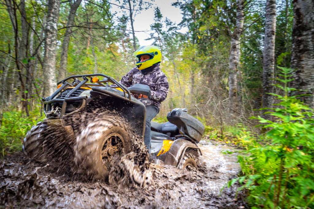 Blog - Man on ATV rides on a dirt road. Powerful transport. Off-road trip. Extreme rest. A trip through the autumn forest. Racing in nature.