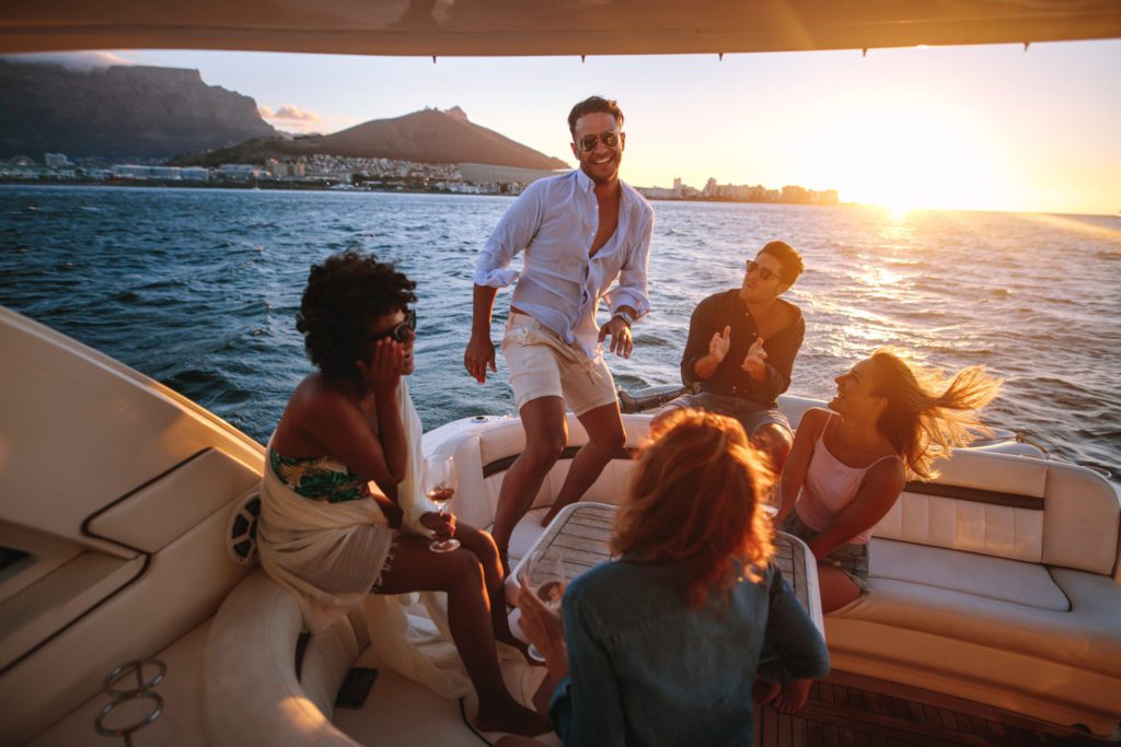 Blog - Group of young people dancing in boat party. Multiracial friends having fun in sunset yacht party.